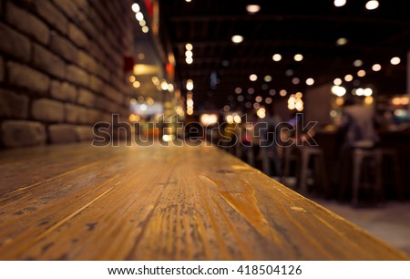 Empty of wood counter bar with blur cafe restaurant in dark background/selective focus .For montage product display