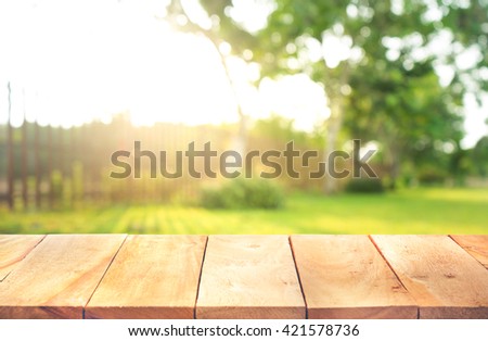 Wood table top with fence and grass in garden background.For  create product display or design key visual layout