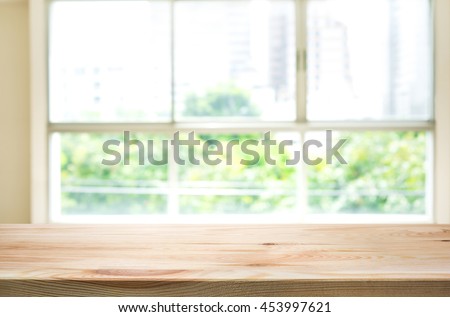 Empty of wood table top on blur of window glass and abstract green from garden with city view in the morning background.For montage product display or design key visual layout background.