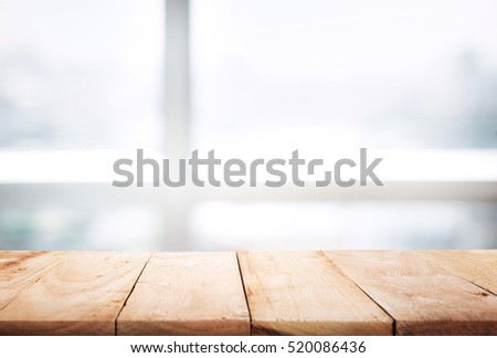 Empty of wood table top on blur of abstract window with sunlight background in winter,Table with window glass in the winter morning background.For montage product display or design key visual layout.
