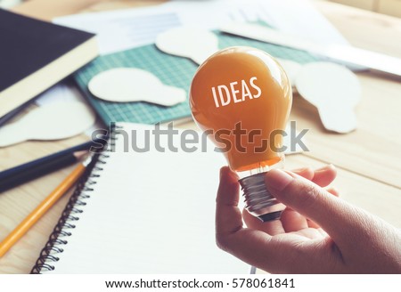 Businessman with lightbulb on desk in workplace. Ideas, creativity, inspiration and start up concept