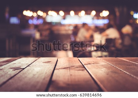 Wood table top with blur light bokeh in dark night cafe,restaurant background .Lifestyle and celebration concepts