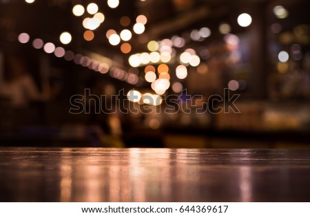 Wood table top with reflect on blur of lighting in night cafe,restaurant background/selective focus.