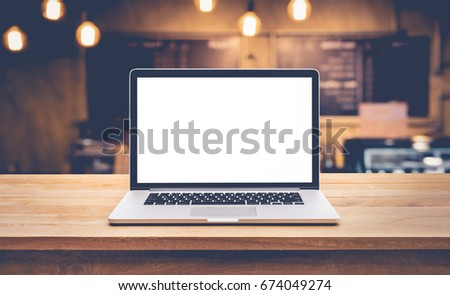 Modern computer,laptop with blank screen on table with blur cafe,restaurant backgrounds