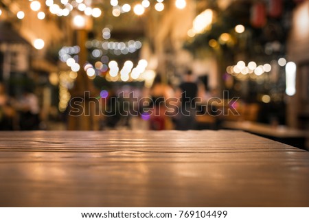 Wood table top with blur of lighting in night cafe restaurant (community) background/selective focus.