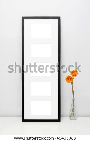 Picture Frame for Home Decoration. Potted sunflowers and a black picture frame on white table against a white wall.