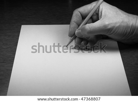 Hand holding pencil over paper