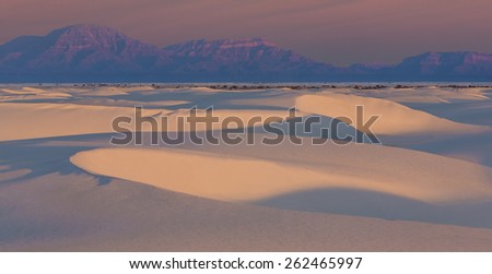 Dune Glow - the white dunes at White Sands National Monument glow at sunrise with mountains and sky in pink.