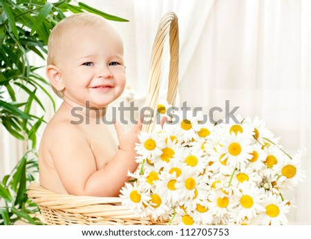funny baby in a wicker basket with daisy flowers