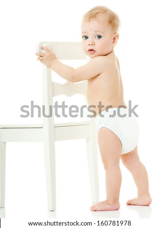 baby holds on to a white chair. isolated.