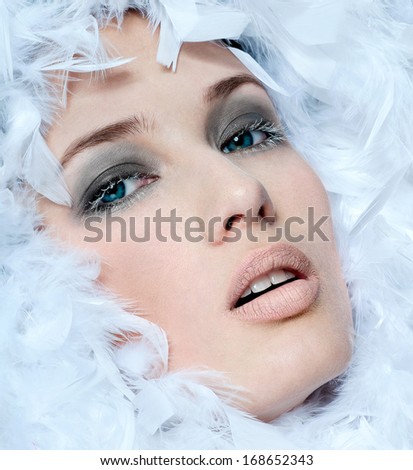 fashionable woman\'s face surrounded by white feathers