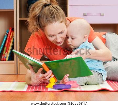 Mother reading a book to little baby son. Indoors