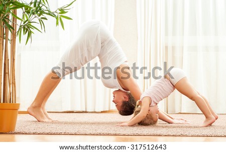 Mother and daughter doing yoga  exercise home. Mother and baby gymnastics.