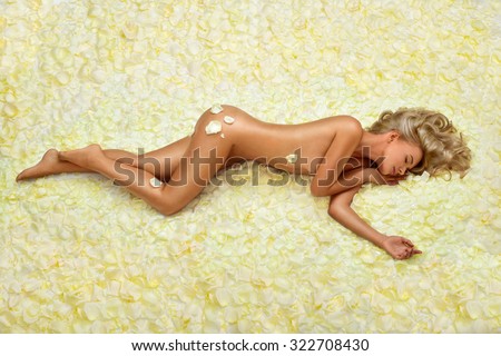 Beautiful slim young woman lying on petals of roses. Perfect figure. Sleeping woman.
