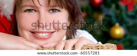 The girl  in a Santa hat near the Christmas tree in a house interior