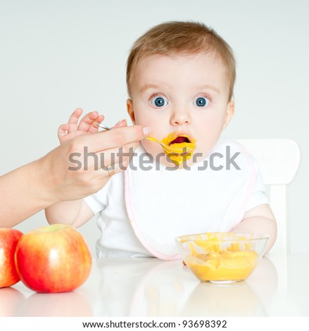 Mum spoon-feeds the child - stock photo