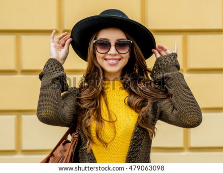 Fashion woman in a hat and sunglasses, in knit dress and jacket outdoors in the fall. Autumn time.