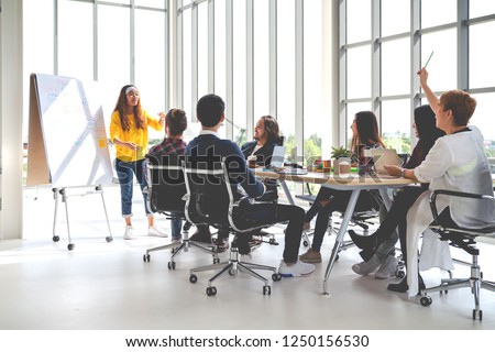 Young asian creative hipster female leader standing and making presentation at modern office happy talking marketing idea with team. Casual asian people business meeting workshop soft tone concept.