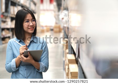 Candid of young attractive asian woman, auditor or trainee staff working in warehouse store counting or stocktaking inventory by smart tablet. Asian entrepreneur, small business or SME concept.