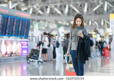 Charming beautiful business woman smile in casual style using smartphone with blur the airport terminal.