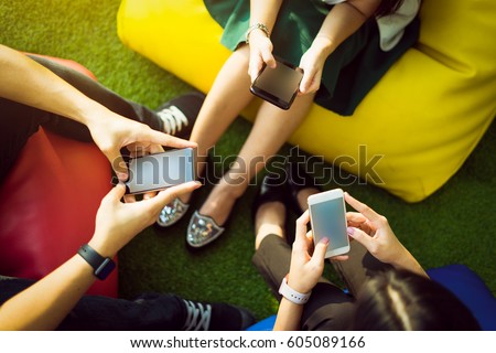 Group of three young people using smartphones together, modern lifestyle or communication technology gadget concept.