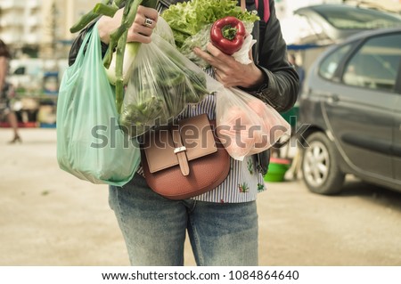 Close up on person buyer hold groceries in bags. Buy sell process. Choosing healthy wellbeing lifestyle, vegetables background