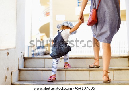 Back view of beautiful toddler girl walk with mother, stairs outdoors background, closeup view