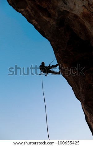 Climber on the rock against the blue sky