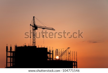 Industrial landscape. Construction cranes and concrete structure at sunset