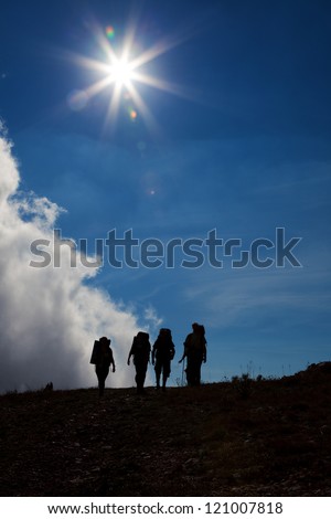 Silhouettes of tourists on against a blue sky with sun and clouds