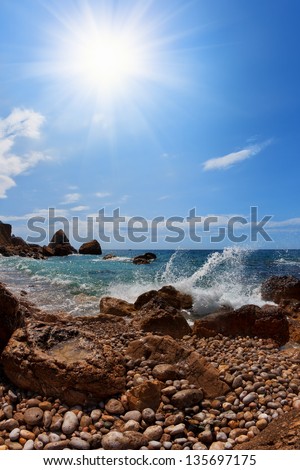 Beach. Rocks, sea and sun on a blue sky