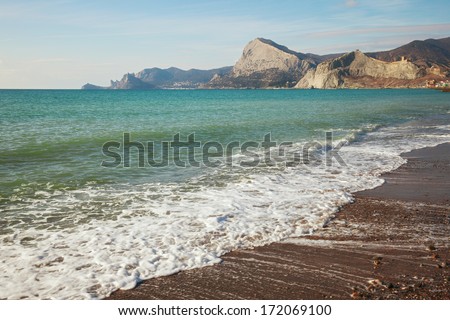 Waves on the beach against the backdrop of coastal mountains