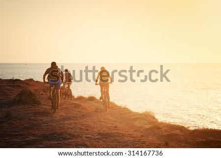 Silhouettes of cyclists on the beach