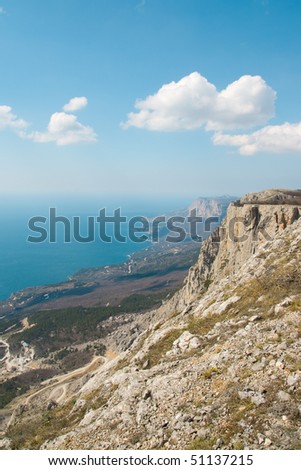 High mountains above the sea and blue sky with clouds.