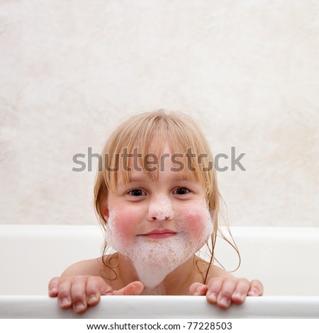 The child is bathed. Face little girl in the foam from the shampoo