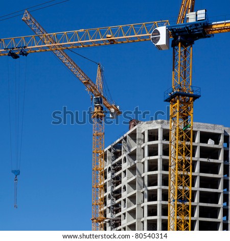 Two construction cranes rise above the building