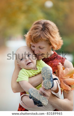 Young mother and son walking in the park and collecting fall leaves