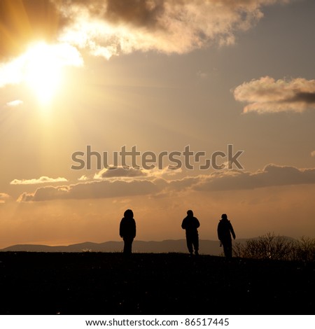 People go to heaven. Silhouettes of four people in the background of sky with clouds at sunset