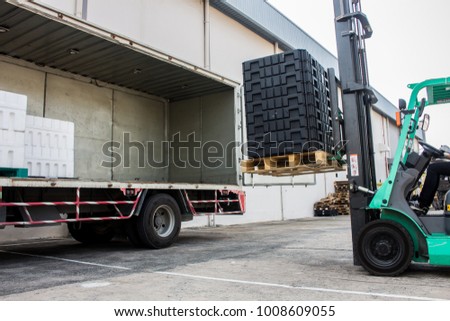 The worker loading pallet with a forklift into a truck.
