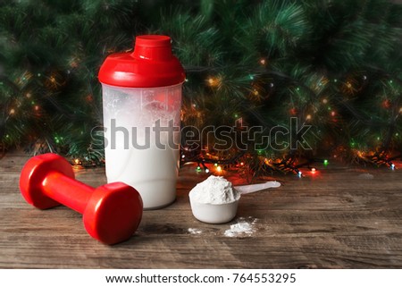 Whey protein shaker. scoop and training dumbbell on christmas background. Sports nutrition