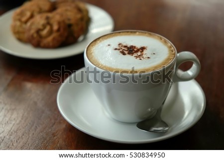 Cappuccino coffee on wood table and bakery background and morning light background