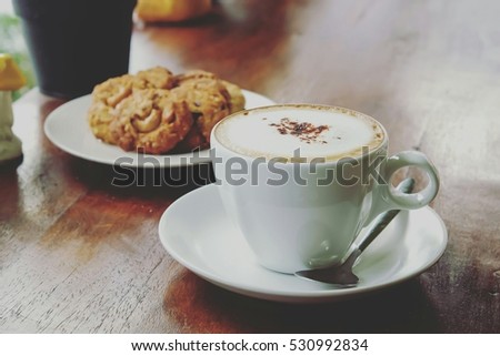 Cappuccino coffee on wooden table and bakery background and vintage background