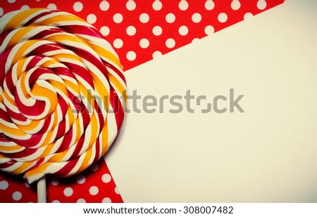 A retro looking photo of a lollipop on a red polka dot background and a list of paper for your text.