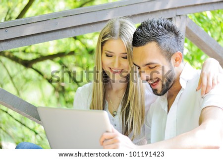 Man and woman using laptop outdoors