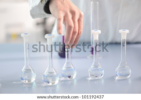 Mens hand holding one of the chemical flasks in laboratory