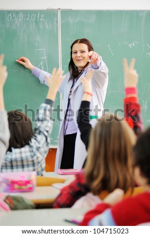 Teacher in classroom and looking at students who raised their arms