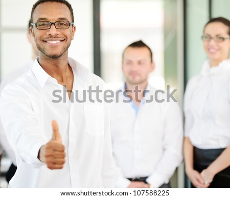 Business person giving you thumb up with colleagues in background