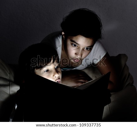 Cute kids reading a book at night