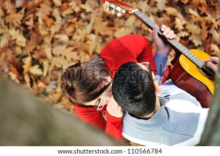 Portrait of love couple playing guitar in park