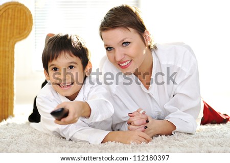 Mom with son lying on floor and watching tv using remote control